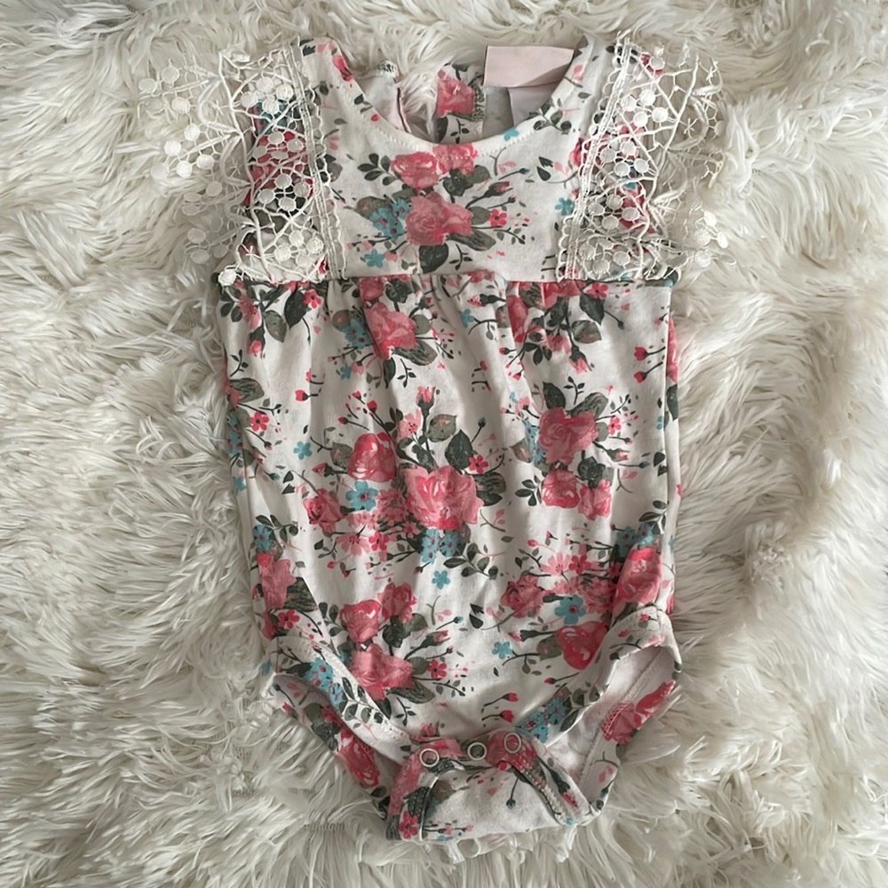 Floral pink and blue onesie with crochet detail on shoulder